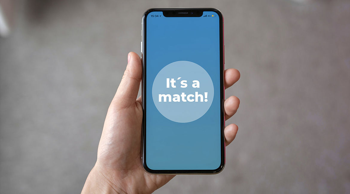 Ein Smartphone, das in einer Hand gehalten wird. Der Bildschirm zeigt in blau "it's a match" an.