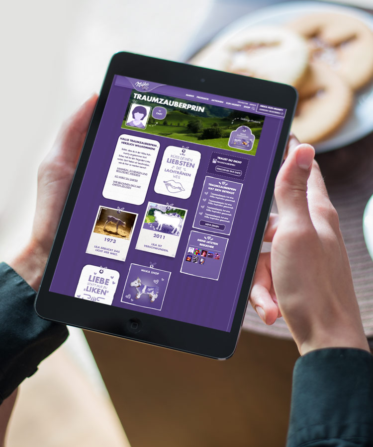 Ein iPad das die Milka Website anzeigt und von zwei Händen gehalten wird.